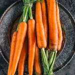 carrot greens on the dark plate and concrete table