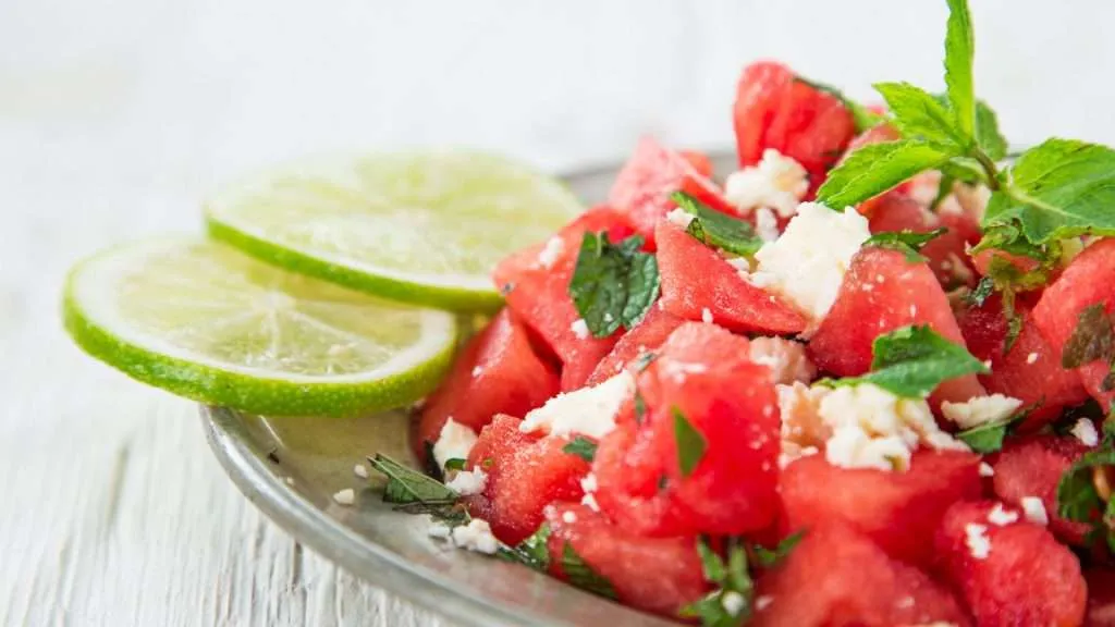 watermelon salad with cheese with lime on the side on the glass plate