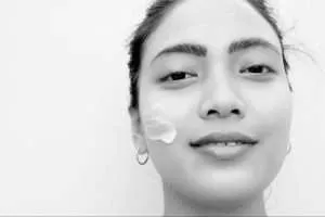 smiling lady using face skin care by awild